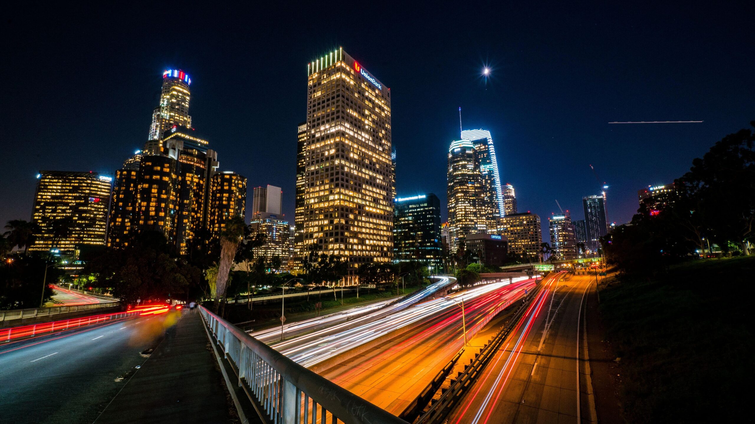 Downtown Los Angeles skyline at night with freeway light trails on the 110, on the way to a late-night chauffeur pickup